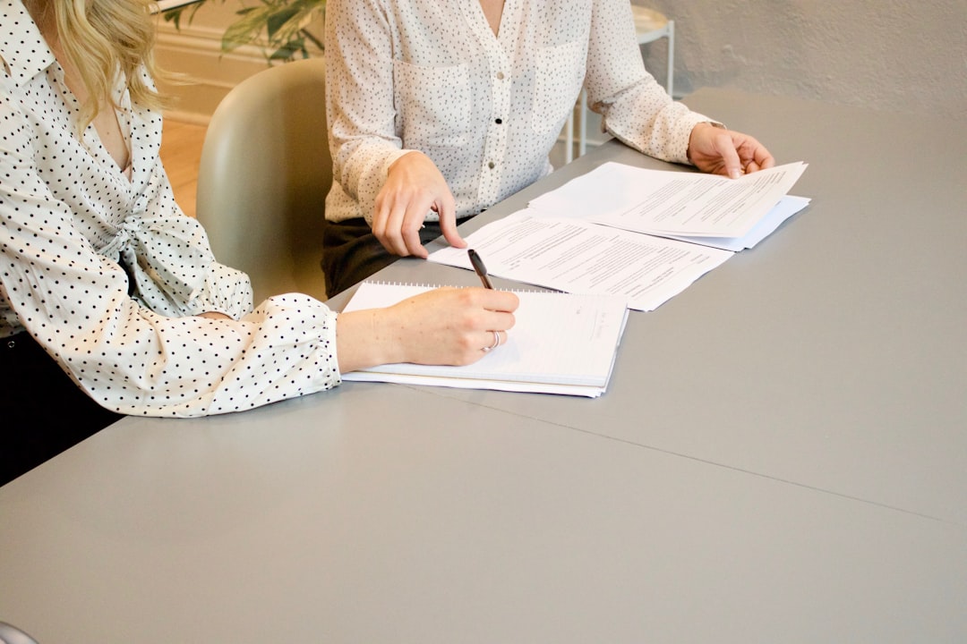 portfolio-04 woman-signing-on-white-printer-paper-beside-woman-about-to-touch-the-documents-hjckknwcxxq